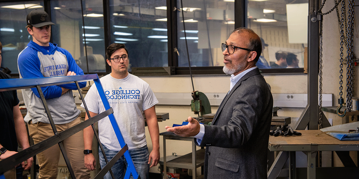  professor speaks to two students in a classroom